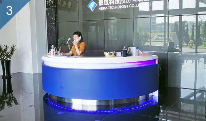 聚恆科技玄關大廳招待區-玄關大廳形象牆整體以祧高的灰色玻璃建構而成，牆面上方延伸到玻璃屋頂引入採光，前方為招待桌。
